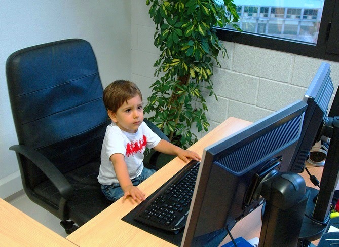baby sitting at a big computer