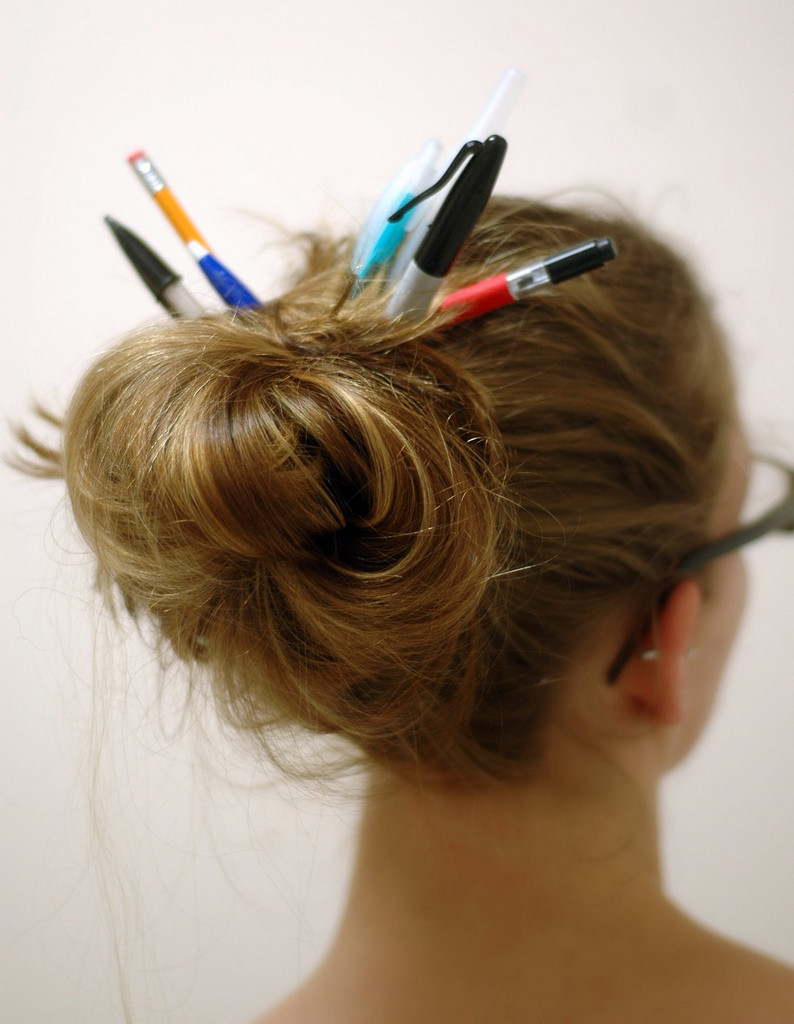 pens and pencils in a messy bun