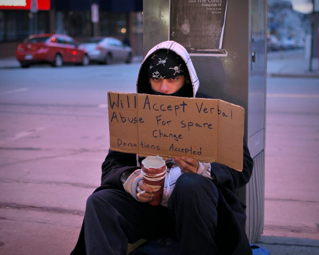A panhandler whose sign says, "Will accept verbal abuse for spare change." Photo by Morgan.